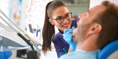 a dental assistant with expanded functions holding an instrument while looking into the mouth of a patient