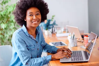 A woman sitting at a desk working on a laptop computer.