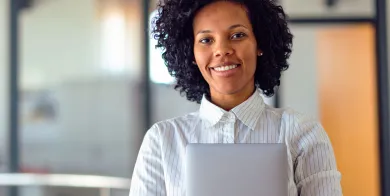 a healthcare accounting grad smiling while holding a tablet