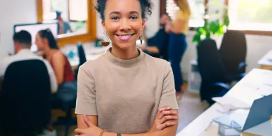 a health information management grad standing in a medical office with crossed arms and smiling