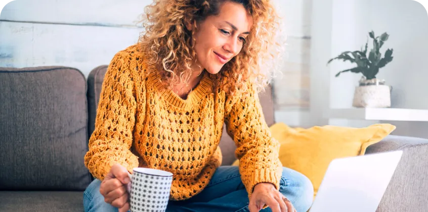 a woman drinking coffee and using a laptop computer