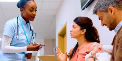 a medical assistant holding a tablet while reviewing a patient’s electronic health record with the patient