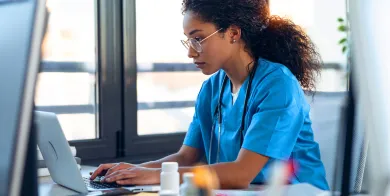 a medical administrative assistant working on a computer in a doctor's office after completing medical administrative assistant training