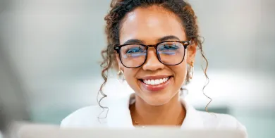 student smiling while sitting in front of her computer and taking online medical billing and coding classes