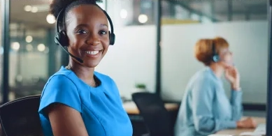 a medical office and billing specialist smiling while sitting at a desk and wearing a headset after completing a training program