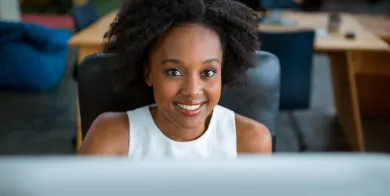 a medical office and billing specialist smiling while working at a computer on her first job