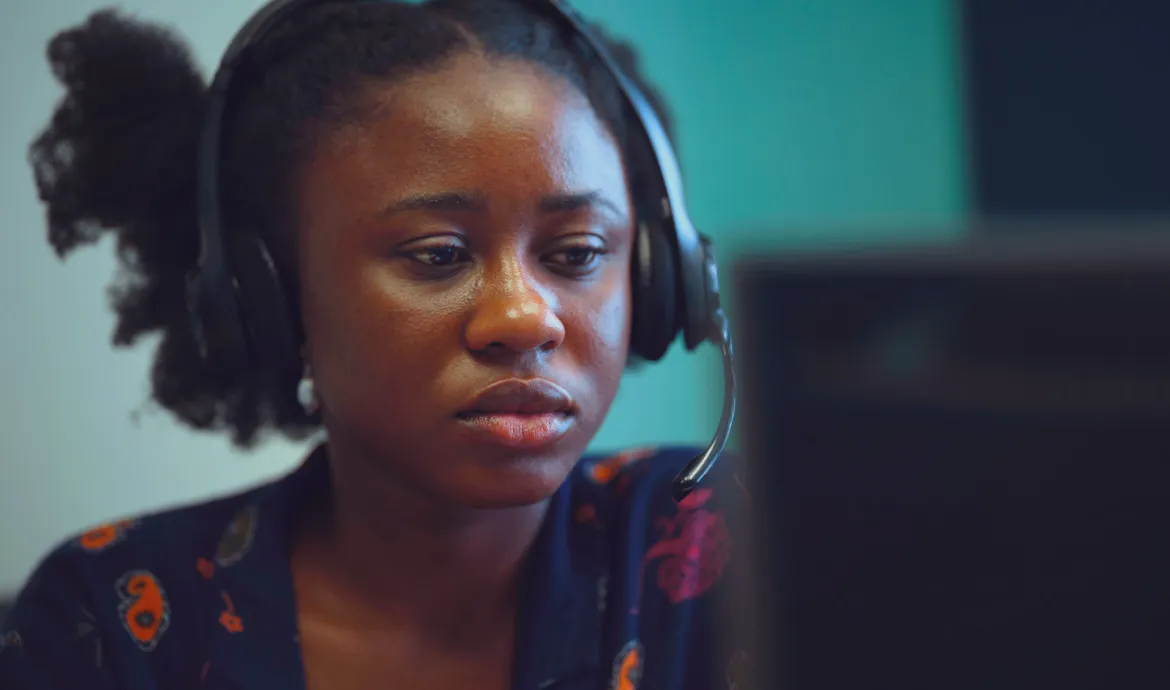 a medical office and billing specialist looking at a computer while wearing a headset