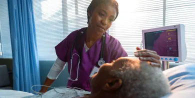 a nursing assistant providing care to an elderly patient who is lying in a hospital bed