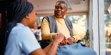 a nursing assistant holding a tablet while talking to a patient and explaining their electronic health records