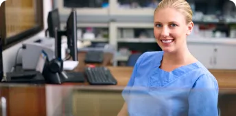 A healthcare professional smiling while sitting at a desk