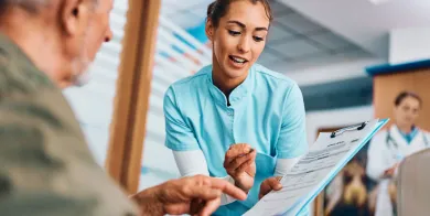 A patient care technician explaining paperwork to a patient after completing patient care technician training