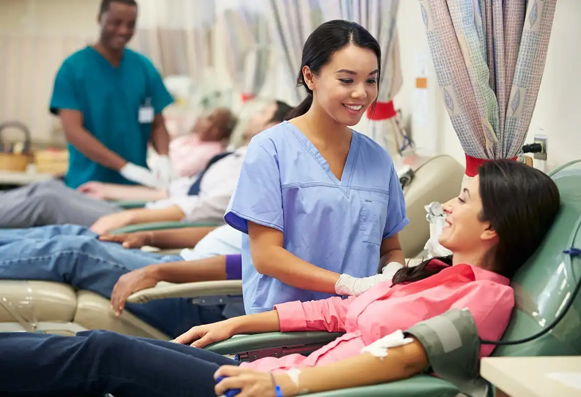 A phlebotomist assists someone giving blood